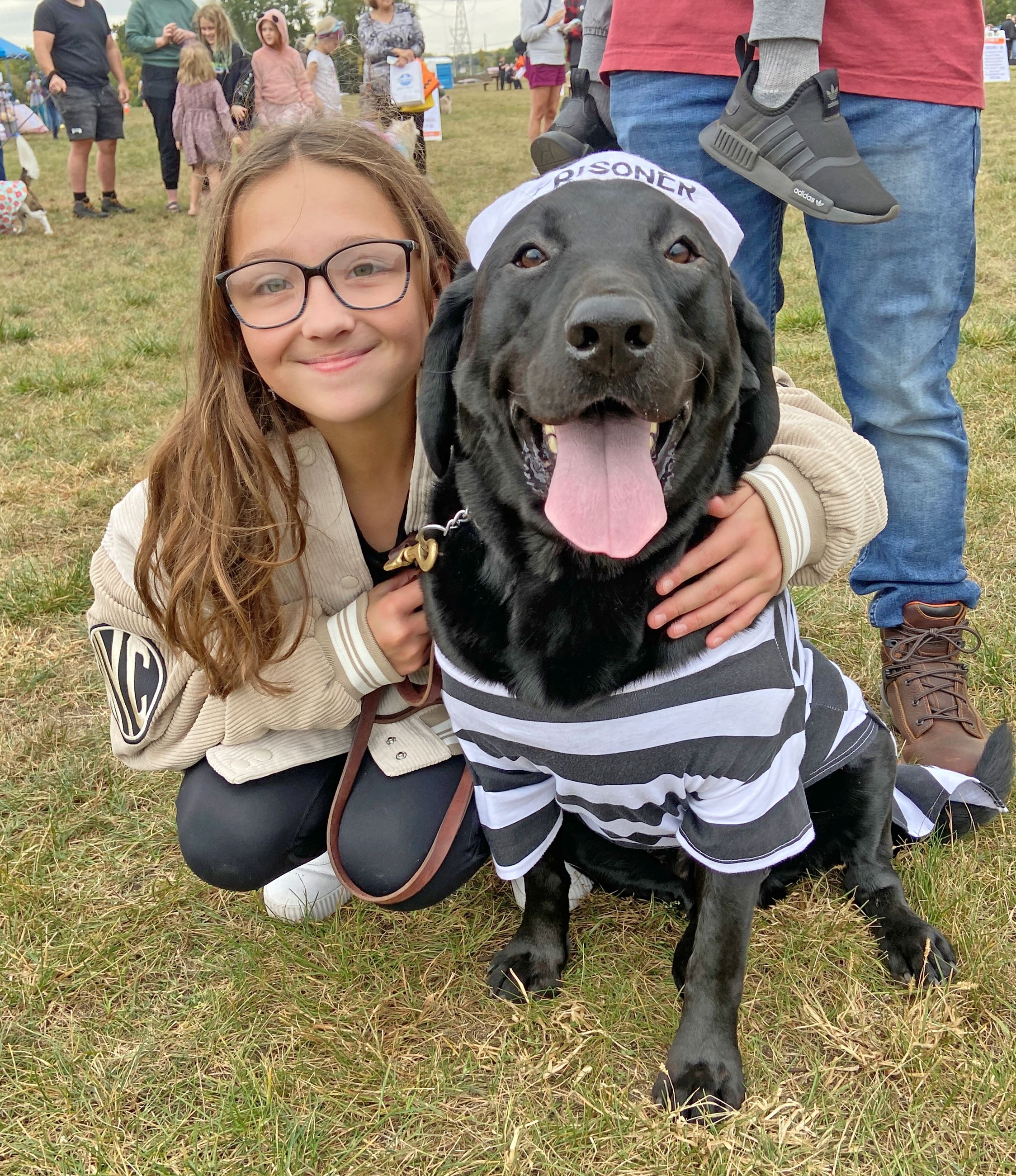 Dog in a prisoner costume with a girl at Let's Pawty
